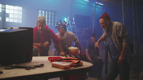 group of men intently watching an event in a workshop