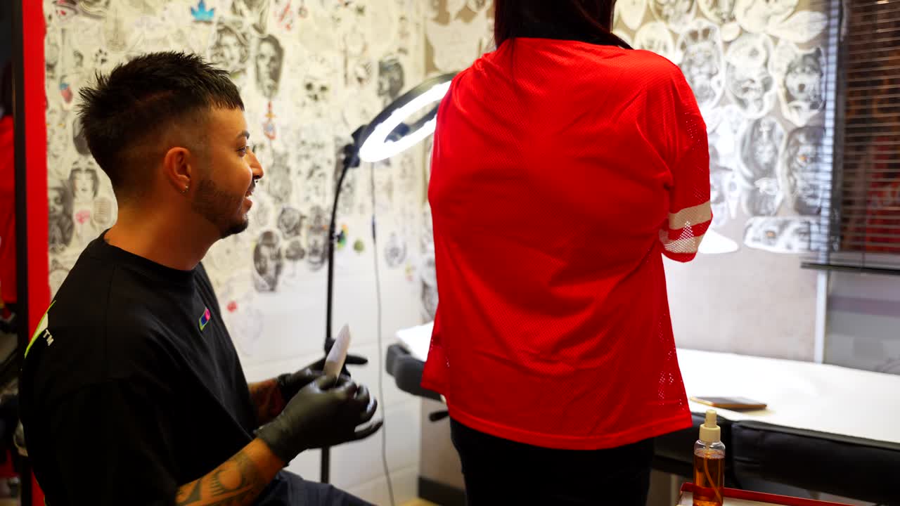 Professionell tatuerare i sin studio placerar referens på kundens arm.