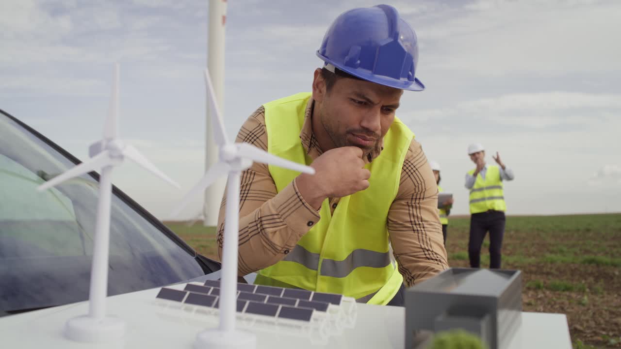 ingenieros latinos pensando en el proyecto de campo con molino de viento.