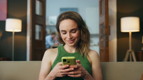 smiling woman texting telephone living room zoom on. woman chatting mobile phone