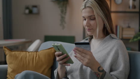 woman using smartphone and credit card for online shopping at home
