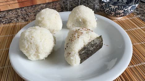 A Plate of Freshly Made Onigiri is Served, With One Topped With Sesame Seeds and Seaweed - Close Up
