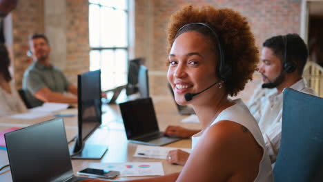 portrait of businesswoman in multi-cultural business team wearing headset in customer support centre