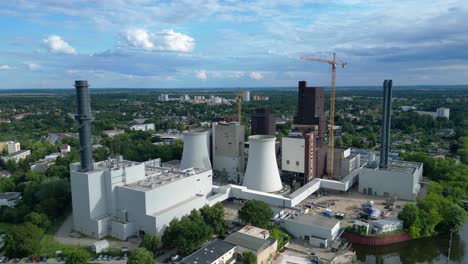 power plant undergoing conversion, retrofitting and renewal, featuring cooling towers, chimneys, and construction crane. great aerial view flight panorama overview drone