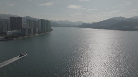 aerial pan shot of boats floating and skyscrapers in hong kong, china