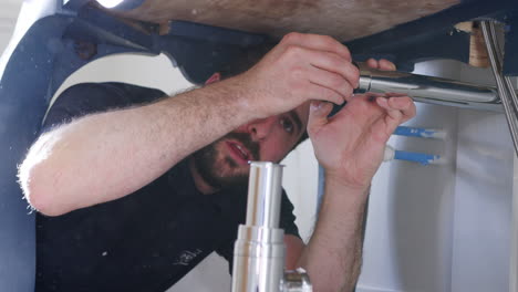 plumber fitting new waste trap to wash basin in bathroom