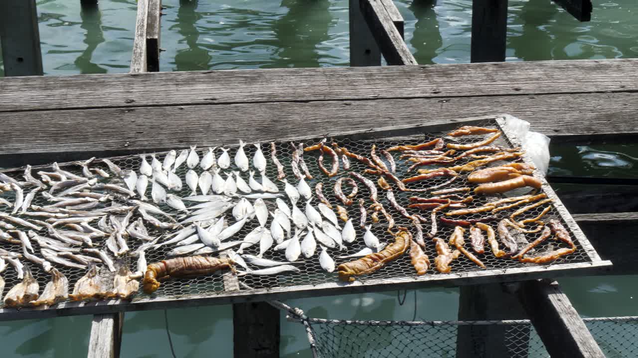 Dried fish arranged on a wooden rack above water, evokes traditional methods
