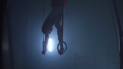 a still shot of a guy working out on the still rings a gymnastics apparatus that is extremely hard in slow motion 180 fps