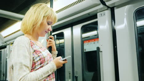 a woman rides in a subway car and uses a smartphone 1