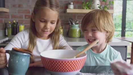 Siblings-preparing-cookie-on-worktop-in-kitchen-at-comfortable-home-4k