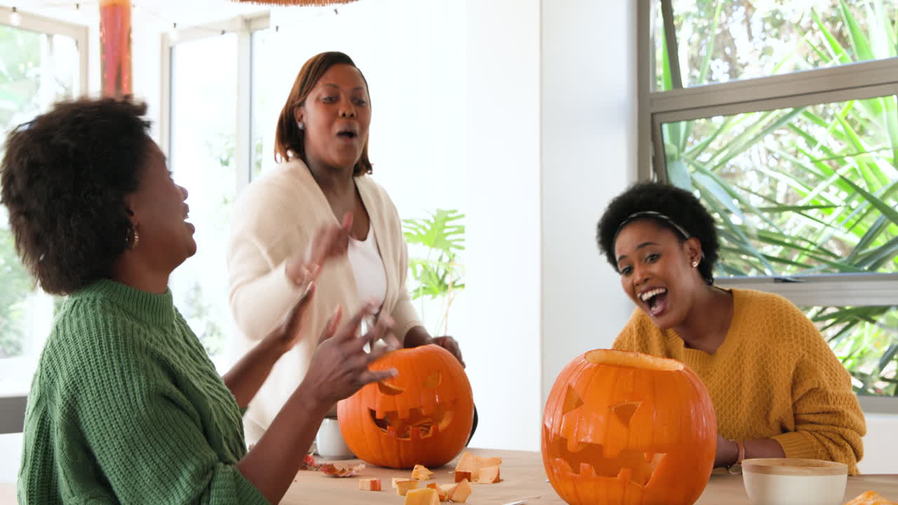 Carving pumpkins, African American women laughing together during fun activity