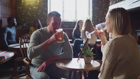 couple meeting for lunchtime drinks in traditional english pub making a toast