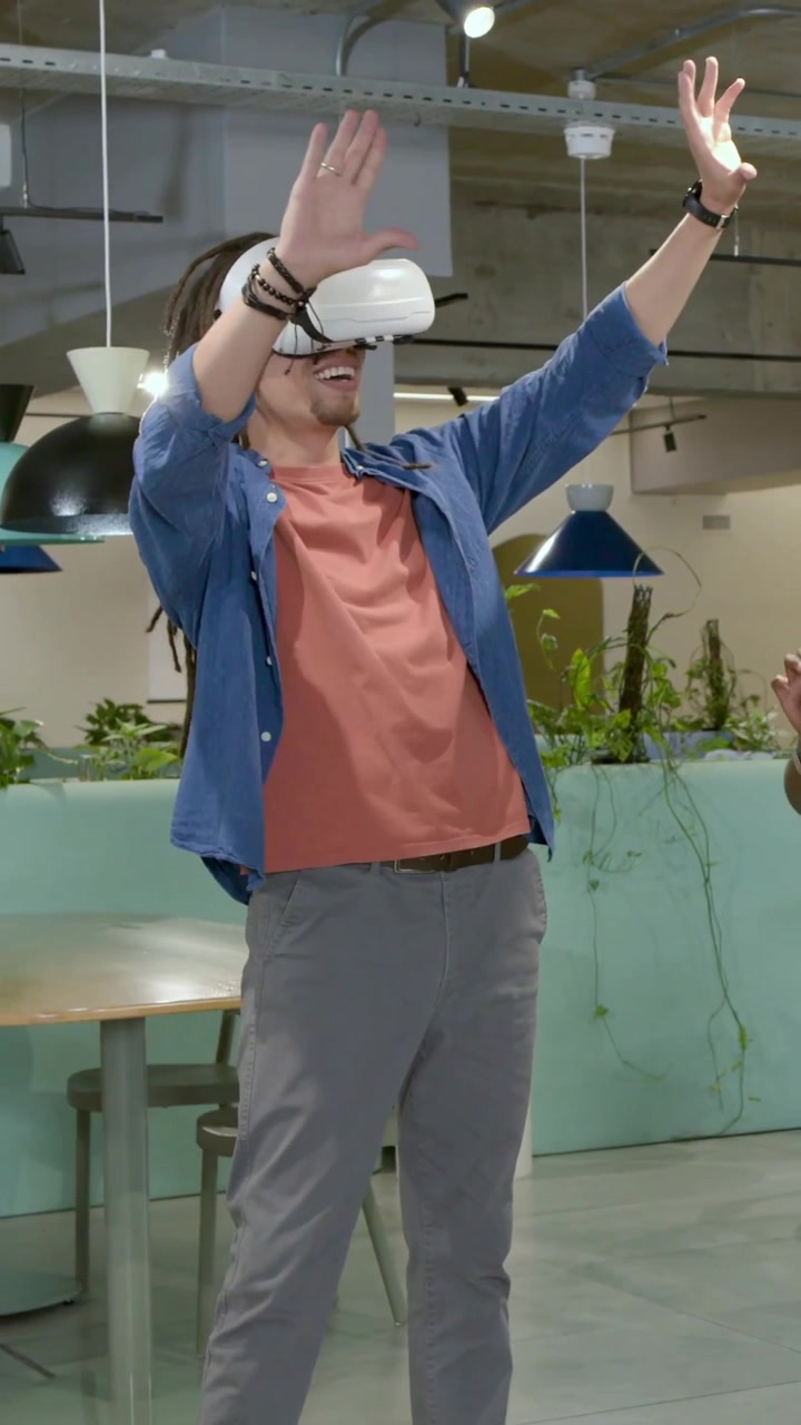 Video verticale: Reazione all'avvio della VR, utente con visore e maglietta color ruggine che pizzica e spinge le mani in salotto.