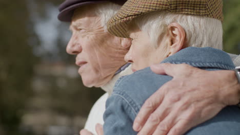 close up of an elderly couple hugging and kissing while spending time in park on sunny autumn day