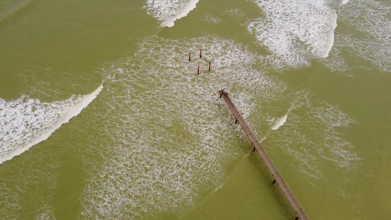 Aerial View of Pier Extending into Ocean with Brownish Green Water