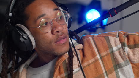 close up of male film sound recordist wearing headphones holding microphone boom pole shooting movie or video in studio 1