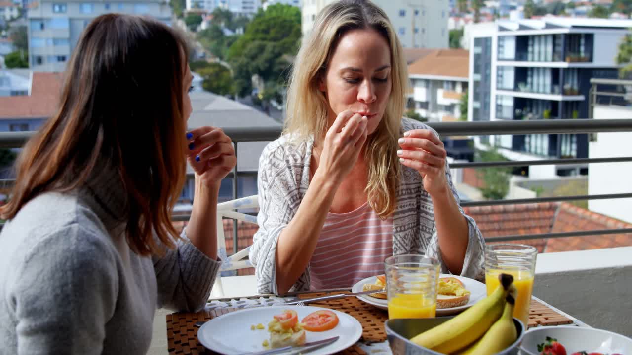 발코니에서 음식을 먹는 레즈비언 커플 4k