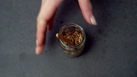 a hand reaching for a jar of sesame seeds and close-up textures