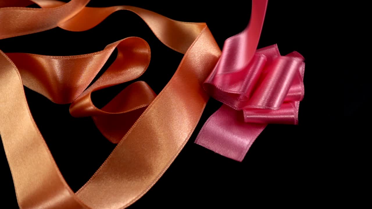 Satin ribbon on a black background. Slow motion