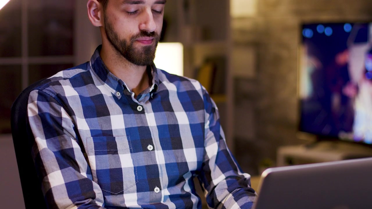 Giovane uomo che lavora al laptop e beve caffè di notte