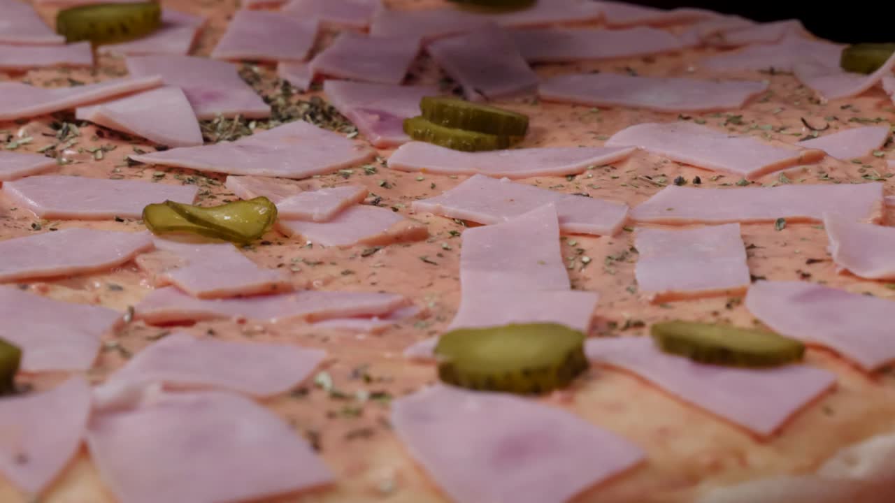 햄과 피클로 피자를 준비하고 있습니다.