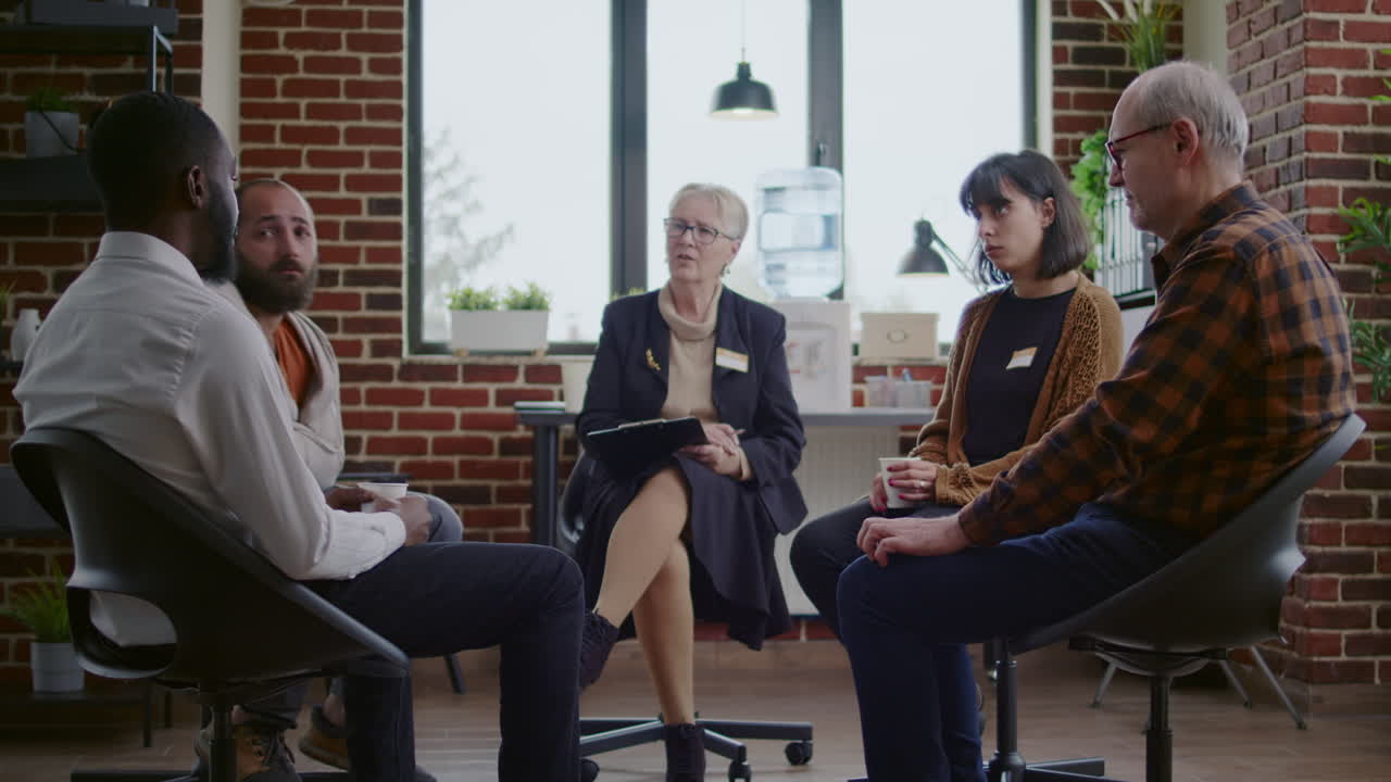Man with addiction meeting with group of people and therapist at aa therapy session