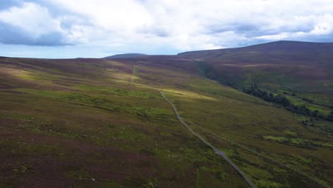 Aerial-Fly-By-over-Irish-Mountain-Landscape-with-a-Lone-Road-cutting-through