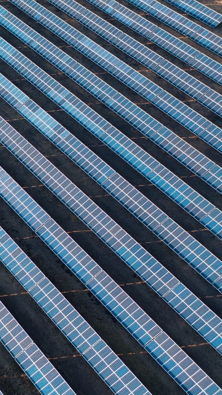 Aerial view of the solar power plant. Rows of blue photovoltaic panels in a field. Vertical video