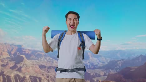 asian male hiker with mountaineering backpack screaming goal celebrating the success while traveling at the top of mountain