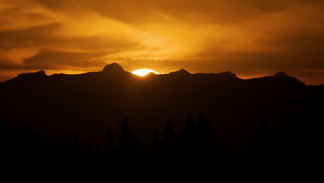 golden sky as sun just about disappears behind mountain at sunset, telephoto