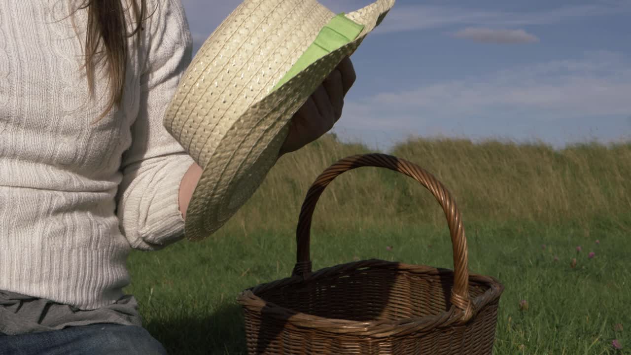 필드 중간 샷에 바구니와 함께 필드에 밀짚 모자를 들고 여자