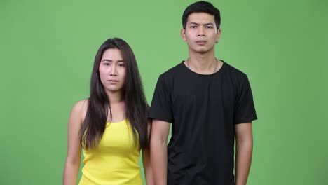 young angry asian couple giving thumbs down together