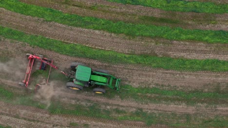 sinfonía de la agricultura: teddy y rastrillo de heno en filas con un tractor verde en los campos circulares de la columbia británica