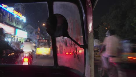 a blurred view from a motorized rickshaw driving down a street at night