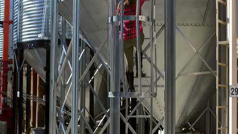 rear view of caucasian female worker climbing ladder by storage tank 4k