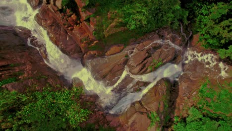 fotografía superior de un avión no tripulado de una cascada que cae sobre rocas rojas en la reserva ecológica de bijagual en costa rica