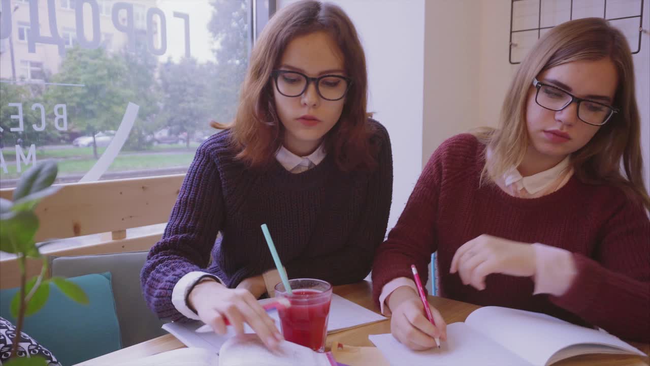 dos chicas estudiando en un café