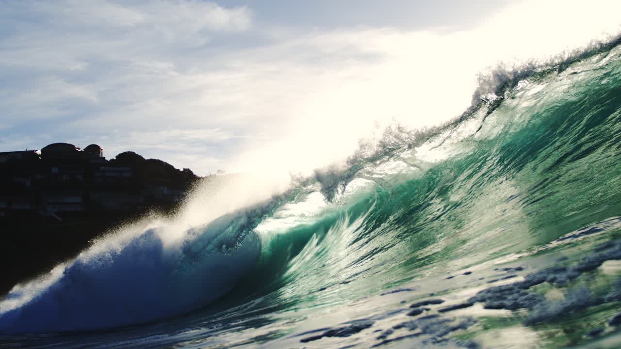 Cinematic flare and sunlight beam over rolling wave lip in artistic telephoto slow motion