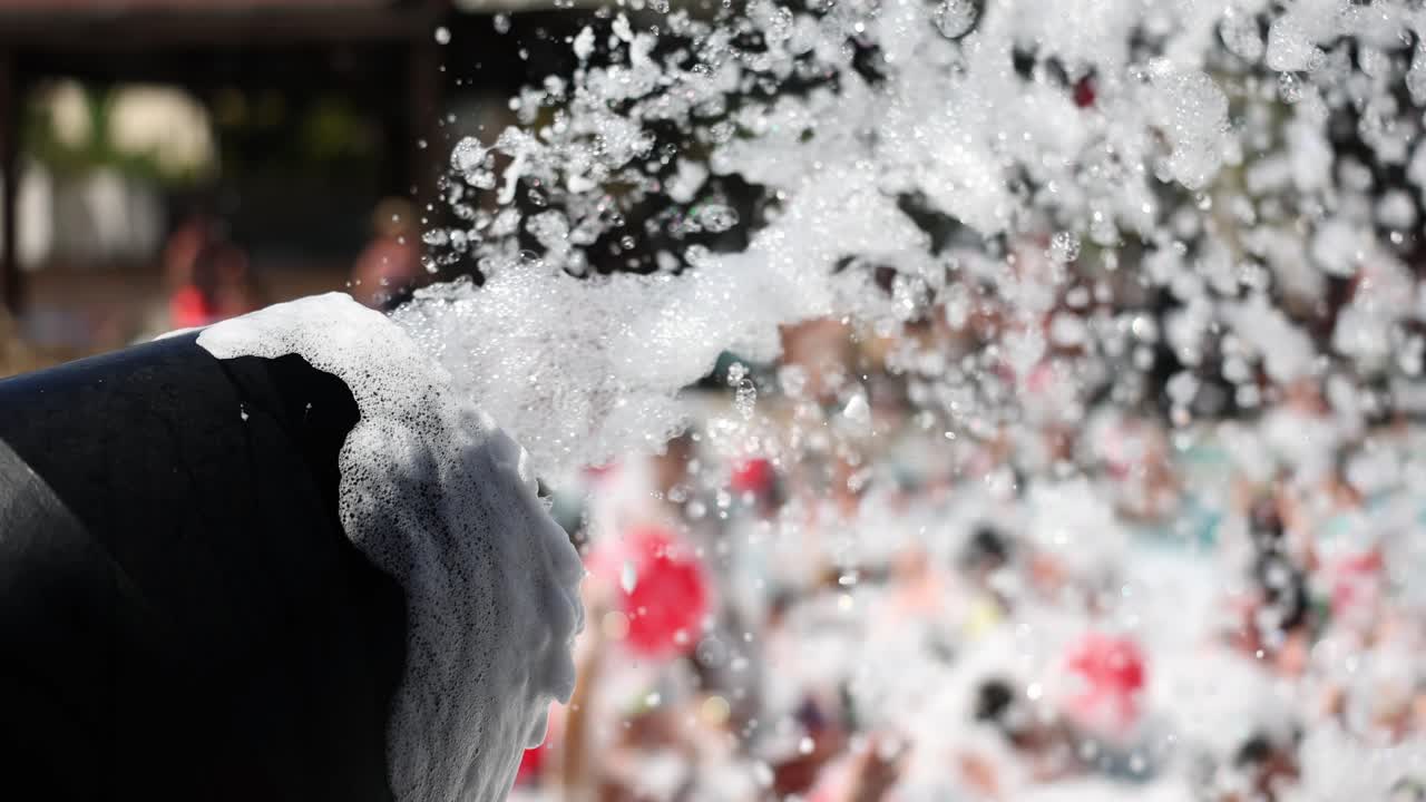 Macchina della schiuma spruzza bolle di schiuma bianca a una festa in piscina