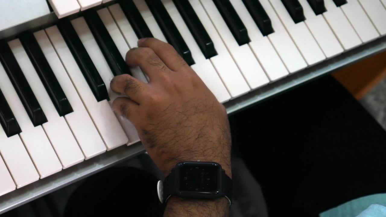 Footage of male hands playing electric organ. Man touches fingers on keys. top view
