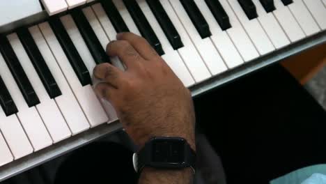 footage of male hands playing electric organ. man touches fingers on keys. top view