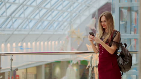 portrait of cheerful teen girl enjoying music in stereo accessory connected to smartphone entertaining on coffee break, smiling woman listening radio broadcast via app on cellular sitting in cafe