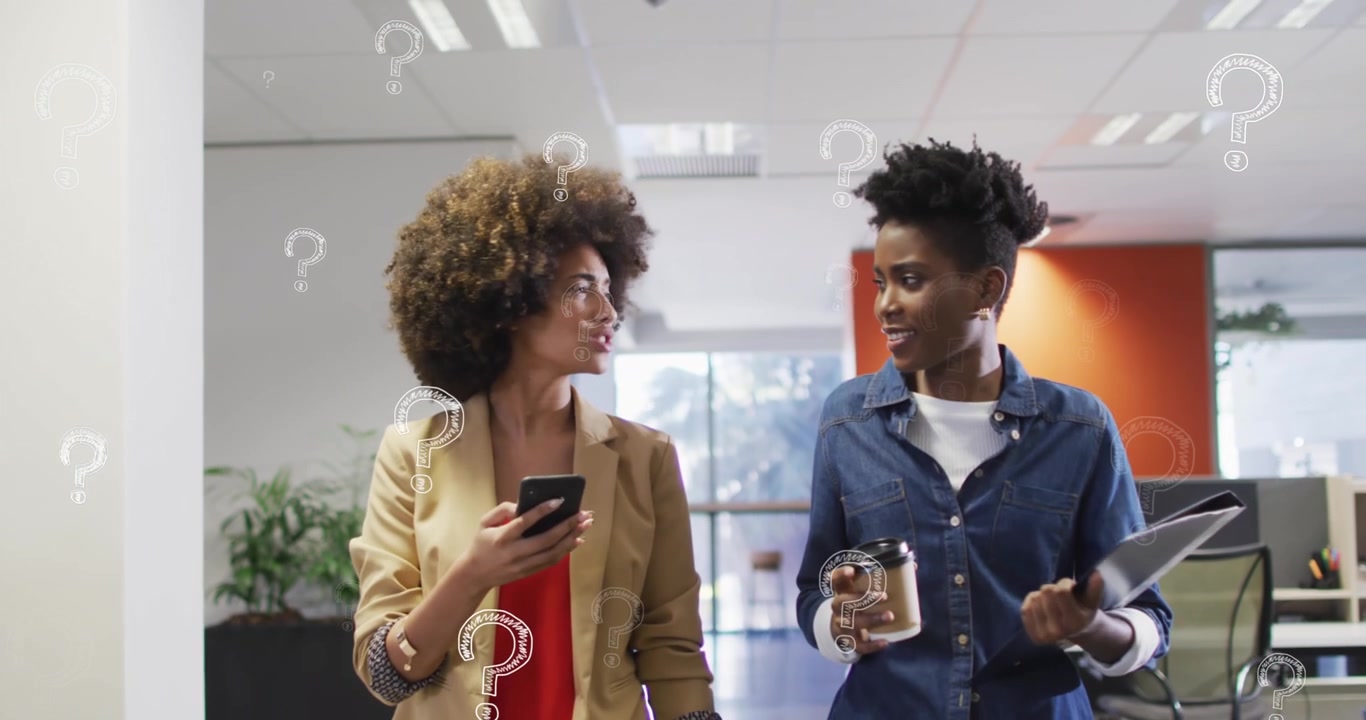 Two Businesswomen Walking and Talking in Modern Office with Digital Question Mark Graphics