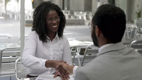 smiling african american woman shaking hands with colleague