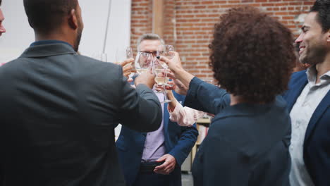 mature businessman makes speech to business team and celebrating success with toast in modern office