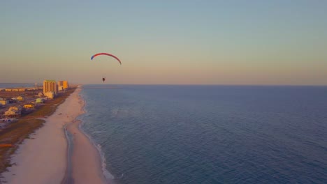 A-paraglider-floats-through-the-sky-over-the-ocean-at-sunset