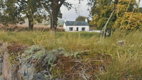 Slow-motion-shot-of-stone-wall-with-a-cottage-in-the-background