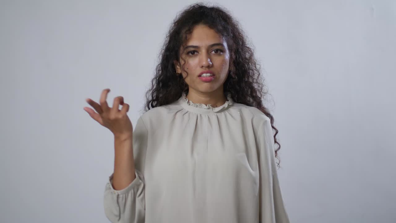 A South Asian woman stands thoughtfully with a calm expression, as if trying to understand or process something complex