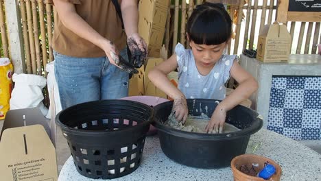 niña asiática mezcla huevos de pato con una mezcla de cáscara de arroz salado, niña prepara huevos de pato para ser conservados, un proceso para cocinar huevos salados