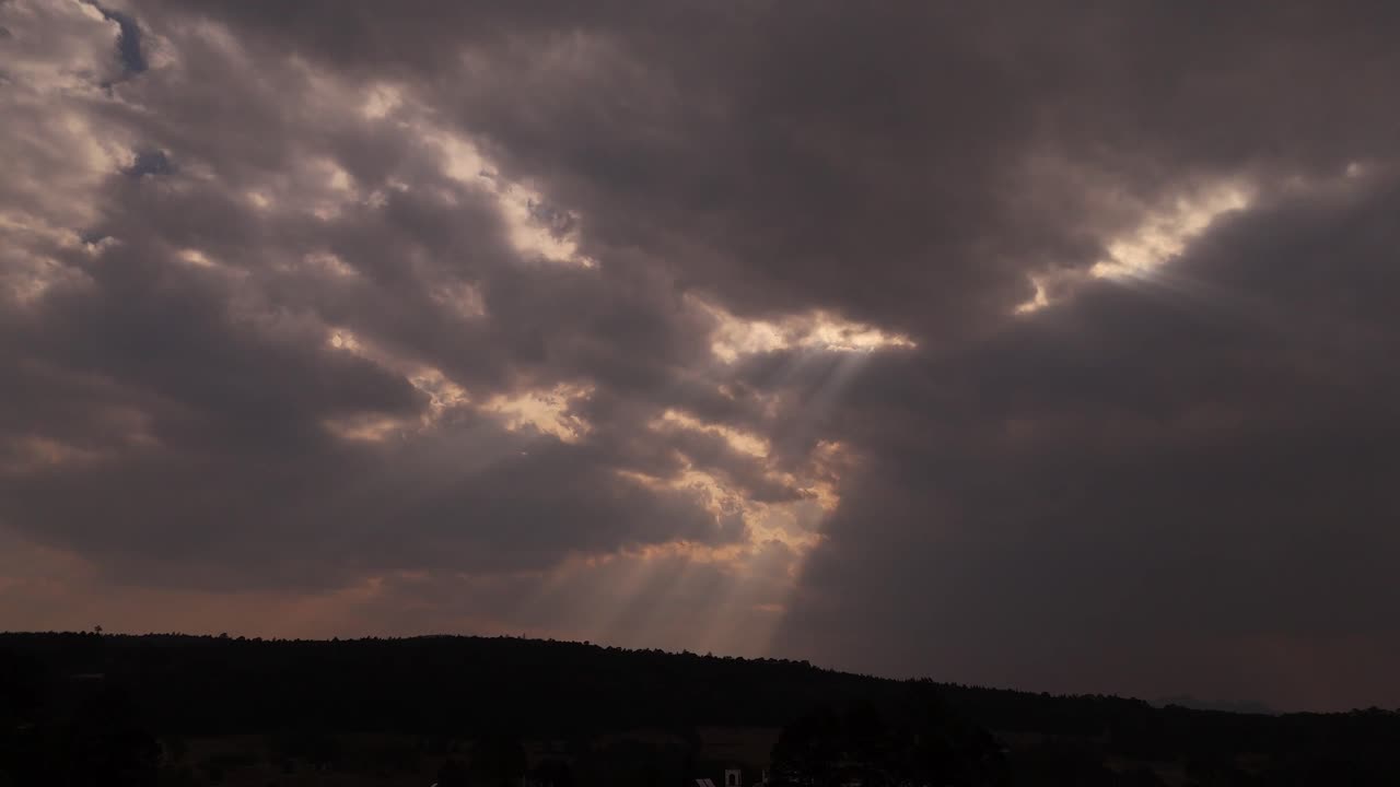 Dark clouds dominate the evening sky, with rays of sunlight breaking through, creating a dramatic scene.